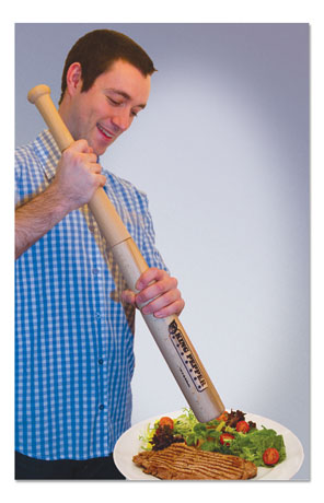 A man grinds pepper on a cooked steak using a full-sized, baseball bat-shaped pepper grinder